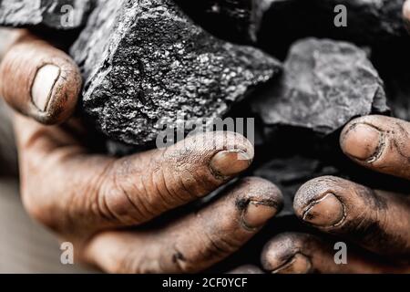 Minatore mani sporche tenendo parte di miniera di carbone di lignite fossile Foto Stock