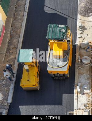 Macchina per pavimentazione che compattano l'asfalto sulla strada. Rullo pneumatico e rullo in acciaio al lavoro. Riparazione della superficie stradale. Vista dall'alto. Foto Stock