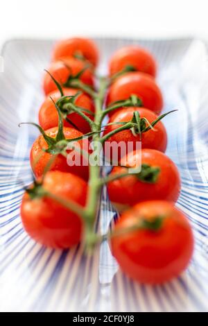 una vite di pomodori ciliegini orizzontalmente su un piatto di ceramica