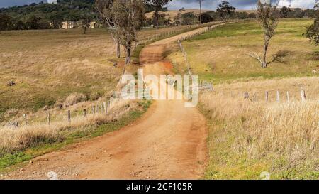 Una strada sterrata rurale tortuosa che conduce attraverso le proprietà casearie in le montagne sono circondate da foresta pluviale tropicale Foto Stock