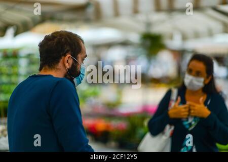 Cremona, Italia - Settembre 2020 Venditore di fiori e piante al mercato settimanale di strada. I giardinieri ed i clienti portano la maschera di faccia e mantengono la distanza- Foto Stock