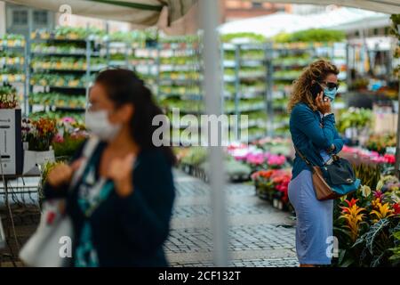 Cremona, Italia - Settembre 2020 Venditore di fiori e piante al mercato settimanale di strada. I giardinieri ed i clienti portano la maschera di faccia e mantengono la distanza- Foto Stock