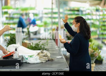 Cremona, Italia - Settembre 2020 Venditore di fiori e piante al mercato settimanale di strada. I giardinieri ed i clienti portano la maschera di faccia e mantengono la distanza- Foto Stock