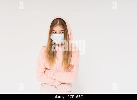 Ragazza teen triste in felpa con cappuccio rosa in maschera di faccia ragazza in posizione chiusa isolato su sfondo bianco Foto Stock