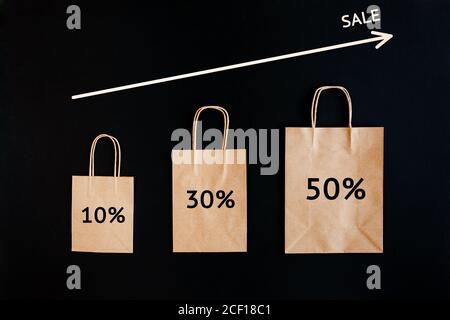 Concetto di sconto per le vendite del Black Friday. Borse di carta artigianali con parola Vendita su sfondo nero. Foto Stock