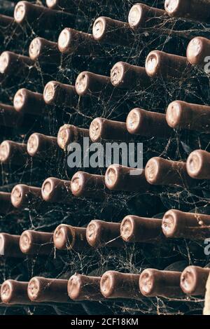 Le bottiglie di vino impilati nella vecchia cantina close-up sullo sfondo Foto Stock