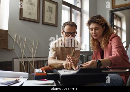 Gruppo di designer seduti al tavolo che esamina i modelli e discutere il progetto in team presso l'ufficio moderno Foto Stock