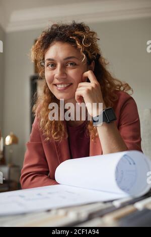 Ritratto di un designer di successo che sorride alla fotocamera mentre lavora con progetto in ufficio Foto Stock