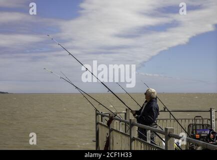 SOUTHWOLD, REGNO UNITO - 05 agosto 2020: Un uomo che pesca dalla fine di Southwold Pier Foto Stock