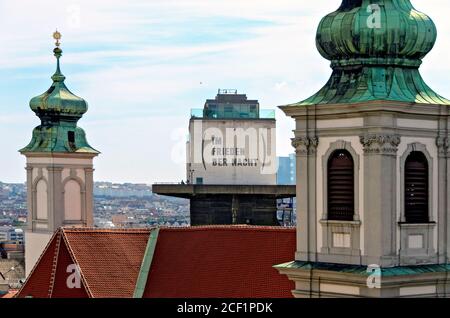 Vista sui tetti e le torri della chiesa di Mariahilfer e l'ex torre in flak con iscrizione artistica a Vienna, Austria Foto Stock