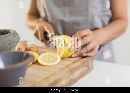 Primo piano donna che affetta limone sul tagliere Foto Stock