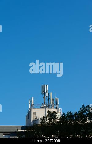 Antenne per telefoni cellulari 5G e 4G installate sul tetto di un edificio. Cielo blu. Spazio di copia per il testo Foto Stock