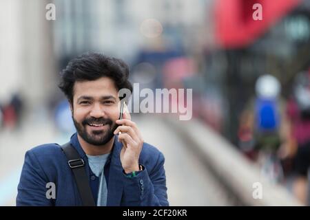 Ritratto sorridente uomo d'affari che parla con lo smartphone all'aperto Foto Stock