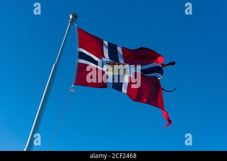 Posta norvegese o bandiera post histed su posta di mailboat ondeggiando nel vento con il cielo blu sullo sfondo Foto Stock