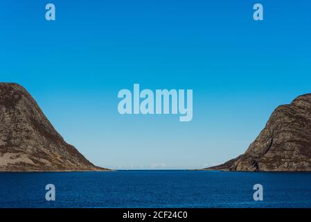 Montagne a forma di U che fieggiano un fiordo sulla costa della Norvegia in giornata di sole con cielo blu Foto Stock