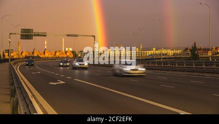 doppio arcobaleno sulla strada d'ingresso della città Foto Stock