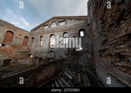 rovine di un vecchio edificio in mattoni, vista interna. luogo storico. mucchi di immondizia sul pavimento, senza tetto. si può vedere il cielo blu Foto Stock