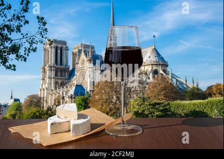 Bicchiere di vino rosso con formaggio brie contro Notre Dame de Paris o la cattedrale di Notre-Dame a Parigi, Francia. Festa romantica. Foto Stock