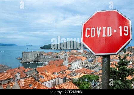 COVID-19 segno contro la vista dall'alto di tetti rossi e mura della città di Dubrovnik, Croazia. Avvertimento sulla pandemia in Croazia. Malattia del coronavirus. COVID- Foto Stock