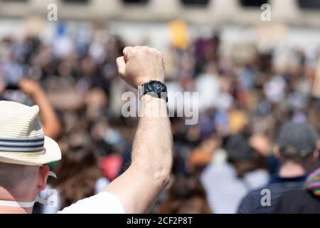 Il pugno di un maschio caucasico si alzò di fronte ad una sfocatura Folla a una protesta Black Lives Matter Foto Stock