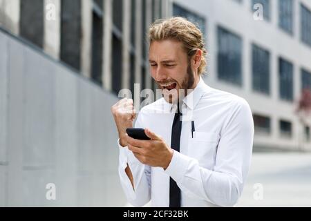 Ritratto di un giovane imprenditore di successo. Un uomo dai capelli ricci in una camicia bianca con un telefono sullo sfondo di un moderno business center Foto Stock