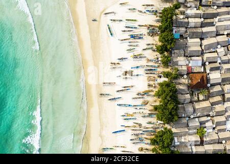 Splendida vista aerea di un villaggio di pescatori con case e barche su una spiaggia di sabbia bianca bagnata da uno splendido mare turchese. Tanjung Aan Beach, Lombok. Foto Stock