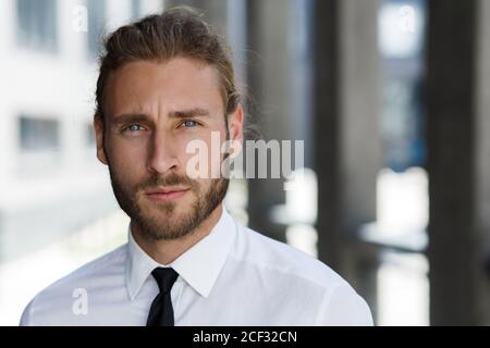 Ritratto di un bell'uomo dai capelli ricci, in stile business. L'aspetto astuto di un uomo d'affari attraente Foto Stock