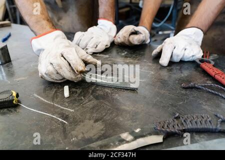 Gruppo di fabbri che fanno coltelli mentre si è in piedi al banco di lavoro in metallo nel vecchio garage Foto Stock