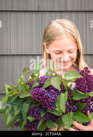 Vista di livello medio di una giovane ragazza con fiori viola e sorridente Foto Stock