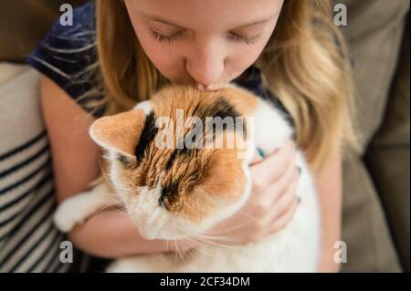 Primo piano di Young Girl Kissing Calico Cat a casa Foto Stock