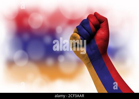 Bandiera di Armenia dipinta su pugno maschile, forza, potere, concetto di conflitto. Su uno sfondo sfocato. Foto Stock
