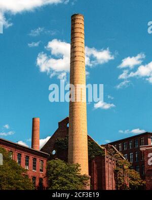 Vista delle pile di fumo d'epoca e degli edifici dei mulini da dietro il centro visitatori del Parco storico nazionale di Lowell su Market St Foto Stock