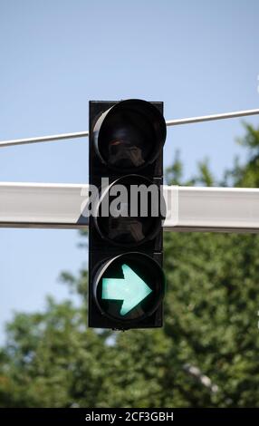 Chiudere il semaforo su un palo di ferro con la luce verde accesa, la freccia mostra il movimento consentito verso destra. Semaforo su sfondo di Foto Stock