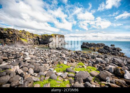 Snaefellsjokull, Islanda paesaggio sentiero vista della spiaggia rocciosa in Hellnar Parco Nazionale Penisola Snaefellsnes con l'oceano e la gente Foto Stock