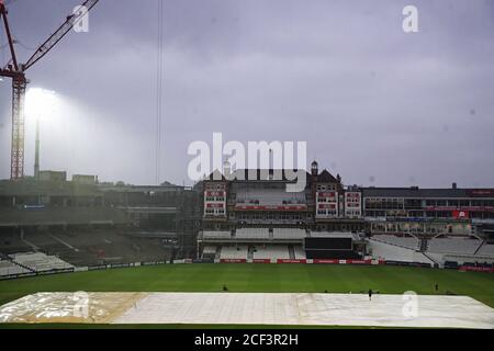 Una visione generale delle coperture sul campo mentre la pioggia cade davanti alla partita Vitality T20 Blast al Kia Oval, Londra. Foto Stock