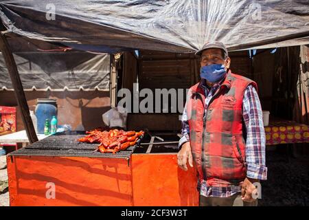 Real De Catorce, Messico. 13 giugno 2020. Un uomo che lavora sulla strada indossando una maschera di vendita di pollo.anche se il numero di visitatori non è paragonabile a quelli prima della pandemia di Covid-19, Real de Catorce in San Luis Potosí Stato ha lentamente iniziato a riavviare l'economia, soprattutto dove il turismo è la principale fonte di reddito. Credit: SOPA Images Limited/Alamy Live News Foto Stock