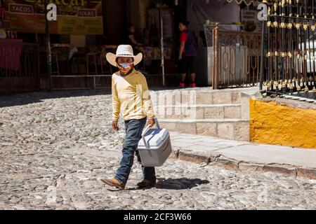 Real De Catorce, Messico. 20 Giugno 2020. Un ragazzo che indossa una maschera facciale come misura preventiva, vendendo cibo per le strade.anche se il numero di visitatori non è paragonabile a quelli prima della pandemia del Covid-19, Real de Catorce nello Stato di San Luis Potosí ha lentamente iniziato a riavviare l'economia, soprattutto dove il turismo è la principale fonte di reddito. Credit: SOPA Images Limited/Alamy Live News Foto Stock