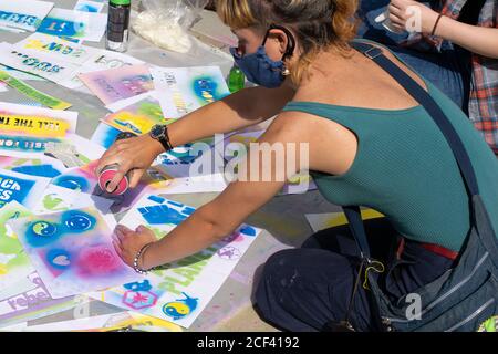 Spruzzatura con stencil usando vernice di gesso cancellabile.Donna con vernice di spruzzo può. Yin e Yang simbolo e slogan. Estinzione ribellione protesta Manchester, Regno Unito Foto Stock