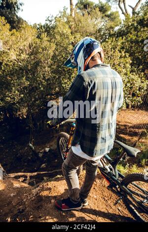 sportivo di mountain bike irriconoscibile in piedi sulla cima della collina in foresta Foto Stock