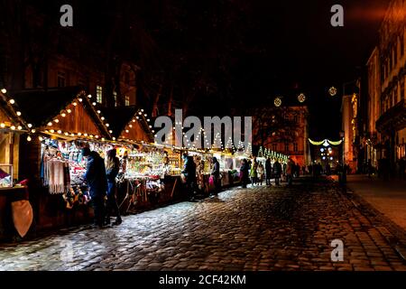 Lviv, Ucraina - 27 dicembre 2019: Piazza del mercato della città vecchia a Lvov con illuminazione di Natale invernale e la gente che acquista souvenir locali regali Foto Stock