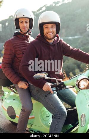 Due uomini con casco che cavalcano una moto scooter e che guardano alla  telecamera Foto stock - Alamy