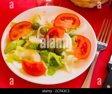 Valenciana tradizionale insalata con foglie di lattuga, ​​tomatoes a fette, la cipolla e le olive con olio di oliva Foto Stock