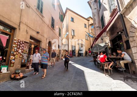 Montepulciano, Italia - 28 agosto 2018: Vicolo in piccolo villaggio in Toscana durante la soleggiata giornata estiva con persone in bar e negozi e sunligg Foto Stock