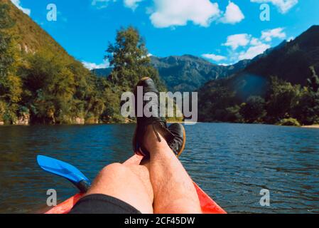 Crop uomo sdraiato su kayak riposando e godendo di montagna idilliaca Paesaggio sul fiume Sella declino in Spagna in estate Foto Stock