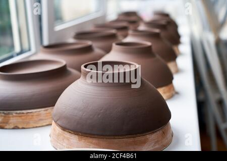 Fabbricazione di prodotti ceramici, pezzi in lavorazione. Primo piano sullo sfondo con pezzi di ceramica contro la finestra. Messa a fuoco morbida, primo piano, messa a fuoco sullo sfondo Foto Stock