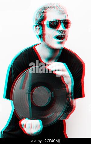 Giovane felice hipster maschio bello in occhiali da sole eleganti che tengono il vinile registra in stile grafico tridimensionale Foto Stock
