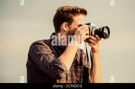 Ragazzo all'aperto cielo blu sfondo. Bella blogger ragazzo viaggiatore telecamera retro. Reporter scattare foto. Impostazioni manuali. Blogger di viaggio. Attrezzature d'epoca. Fotografo hipster. Blogger tiro vlog. Foto Stock