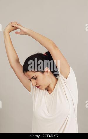 Donna sportiva concentrata stretching e riscaldamento prima di allenarsi su sfondo grigio Foto Stock