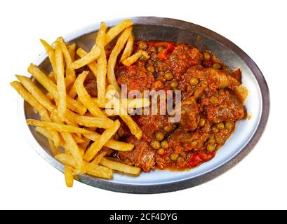 Manzo asturiano stufato con piselli e servito con patatine fritte al piatto. Isolato su sfondo bianco Foto Stock