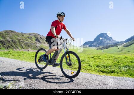 Uomo Equitazione Mountain Bike elettrica o e Bike nelle Alpi Foto Stock